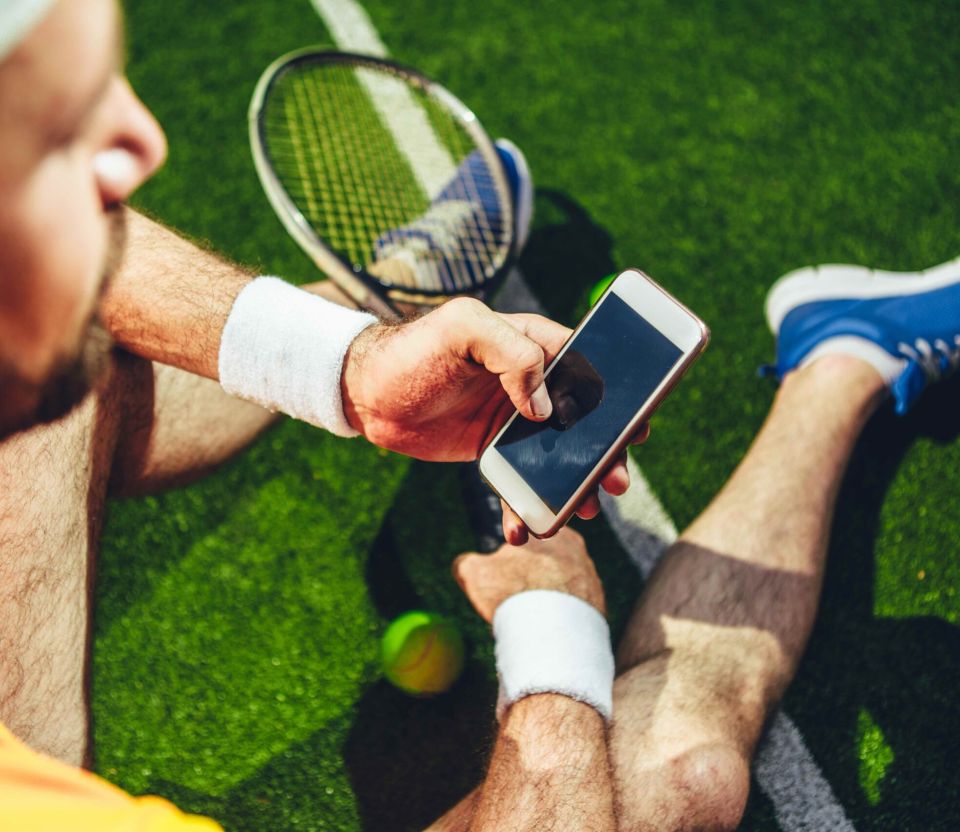 tennisser met mobiel in handen